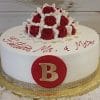 The BR-015 is a round white cake topped with red and white frosting roses, "Felicidades Mr. & Mrs." in red icing, and a large red circle with a gold letter B on the front.