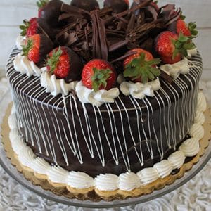 BD-022 is a chocolate cake topped with chocolate-dipped strawberries, chocolate shavings, and whipped cream swirls. It features a glossy chocolate glaze with white drizzle and comes on a gold cake board.