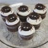 Six CC-058 Spider cupcakes—chocolate with white mousse filling—are topped with spider decorations and arranged on a glass plate.