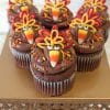 Six CC-071 Turkey cupcake design Gold cakes with chocolate mousse filling, decorated to resemble candy turkeys with colorful icing feathers, are displayed on a gold cake stand.