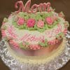 The MD-018 is a round cake with pink and green icing roses, green leaves, and "Mom" on top. "Happy Mothers Day" is written in pink icing. The cake comes on a decorative silver board.