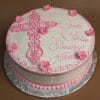 The RC-021 is a round white cake with a large pink icing cross, pink flowers, and "God Bless Emery Jane" in pink script, presented on a silver patterned board.