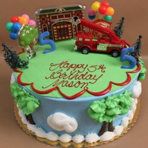The SC-048 Firetruck cake is round and decorated with trees, clouds, a fire truck, number 5 candle, balloons, and a toy fire station. "Happy 5th Birthday Jason" is written in red icing.