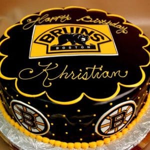The ST-006 Bruins Ganache is a round cake with a glossy black finish, the Boston Bruins logo on top and sides, yellow piping, and “Happy Birthday Khristian” written in yellow icing.