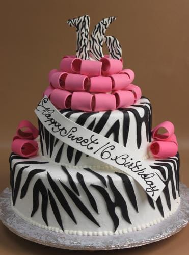 The TC-150 is a two-tier cake with black and white zebra stripes, pink fondant loops, and a large 16 on top. A white ribbon across the cake reads "Happy Sweet 16 Birthday.