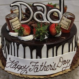 The FD-012 cake features a chocolate drizzle, “Dad” written on top, strawberries, mini liquor bottles, whipped cream, and a “Happy Father’s Day” message on a white plaque at the base.