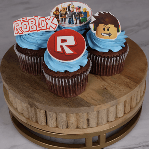 Roblox themed cupcakes topped with blue frosting and character decorations on a wooden stand
