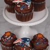 Chocolate cupcakes topped with football decorations, red white and blue sprinkles, and New England Patriots logo toppers