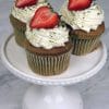 Match cupcakes topped with swirled frosting and fresh sliced strawberries on a white cake stand