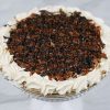 Turtle pie topped with chocolate drizzle, caramel, and chopped pecans with whipped cream border