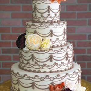 WD-111 is a four-tier white wedding cake decorated with intricate brown piping and clusters of burgundy, cream, and warm-toned flowers.